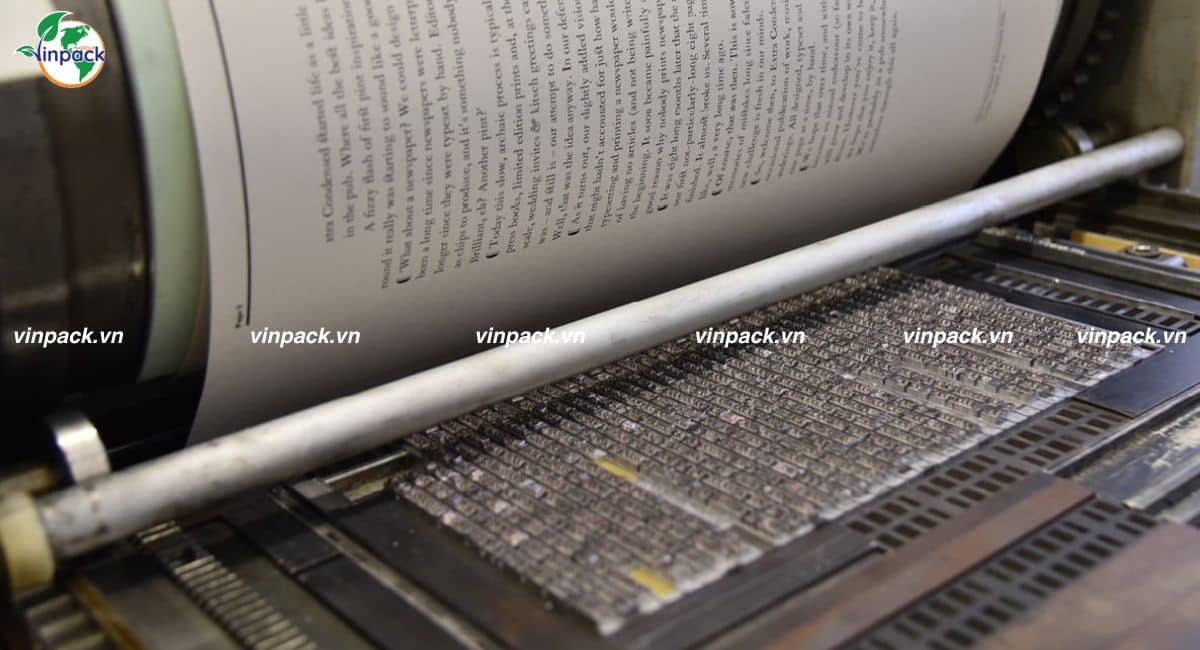 Khuôn chữ kim loại xếp trên bàn máy in typo, tờ giấy in cuộn trên trục
